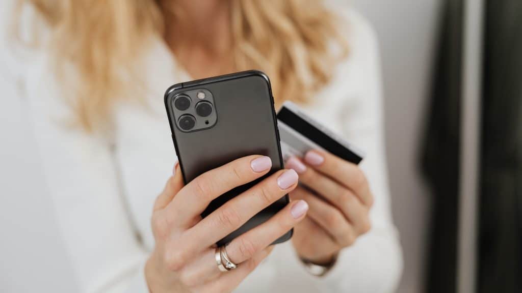 Frau haelt ein Smartphone und eine Kreditkarte
