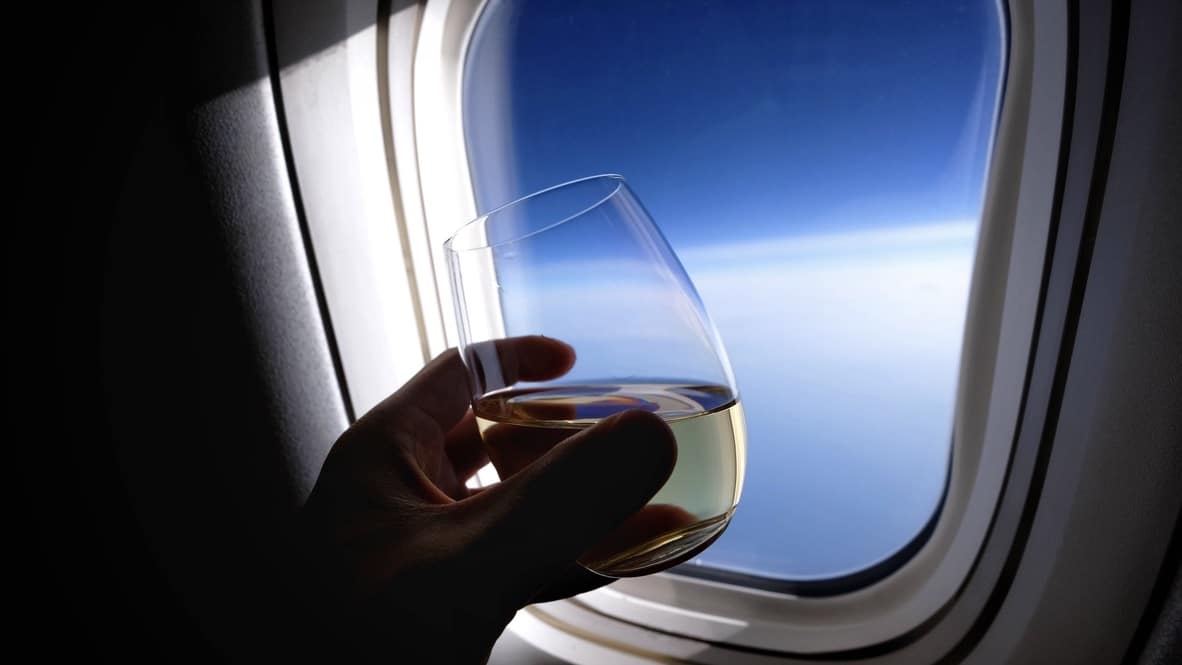 Hand Holding A Glass Of White Wine Near An Airplane Window