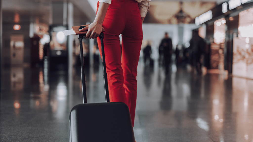 Frau In Roter Hose Und Mit Koffer Am Flughafen
