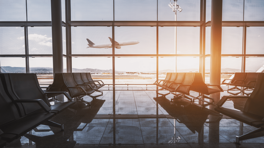 Wartebereich in einem Flughafen mit Blick auf das Rollfeld und abhebendem Flugzeug